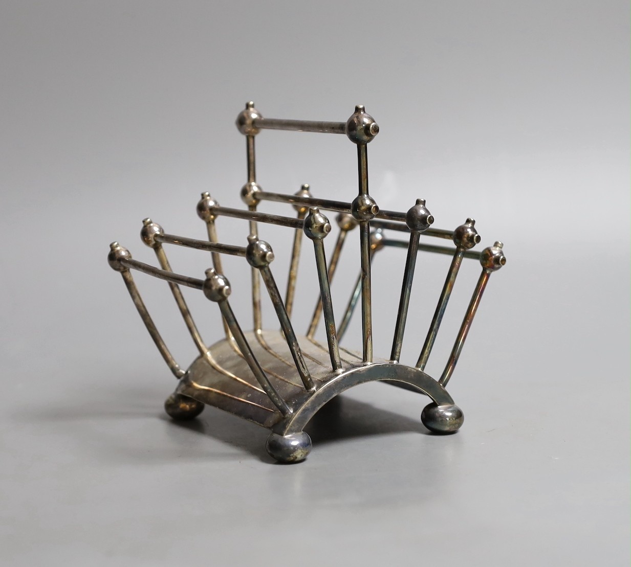 A Victorian Cristopher Dresser for Hukin & Heath silver plated seven bar toastrack, of fan shape, on bun feet, numbered 2556, width 13.5cm.